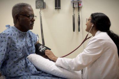 一名身穿病人长袍的非裔美国人正在接受一名身穿白大褂的医科学生的血压测量.